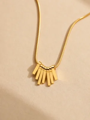 Water-resistant gold fan pendant necklace on beige background
