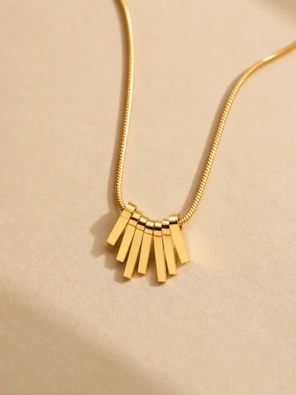 Water-resistant gold fan pendant necklace on beige background