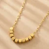 Gold geometric square bead necklace on beige background