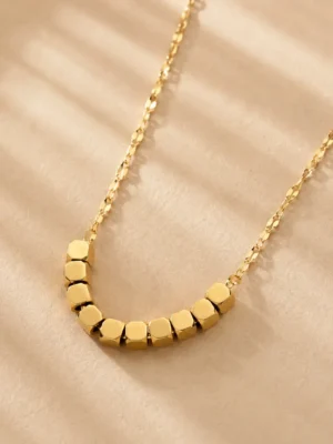 Gold geometric square bead necklace on beige background