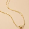 Gold layered bar chain necklace on beige background