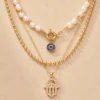 Gold layered evil eye pearl necklace on beige background