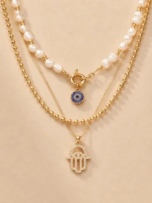 Gold layered evil eye pearl necklace on beige background