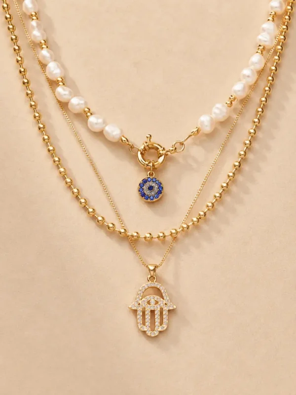 Gold layered evil eye pearl necklace on beige background