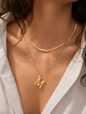 Model wearing gold initial M layered necklace