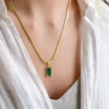 Model wearing gold green stone pendant necklace